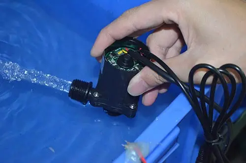 Eine Hand testet und besprüht eine Pumpeneinheit mit Wasser vor dem Einpflanzen.